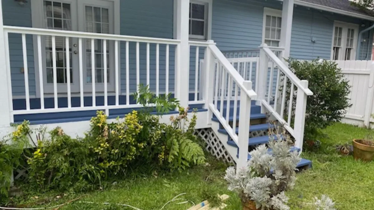 White railed deck with blue trim on light blue house with landscaping