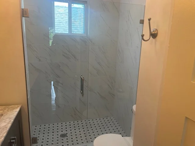 Modern bathroom shower with marble tile walls and mosaic floor